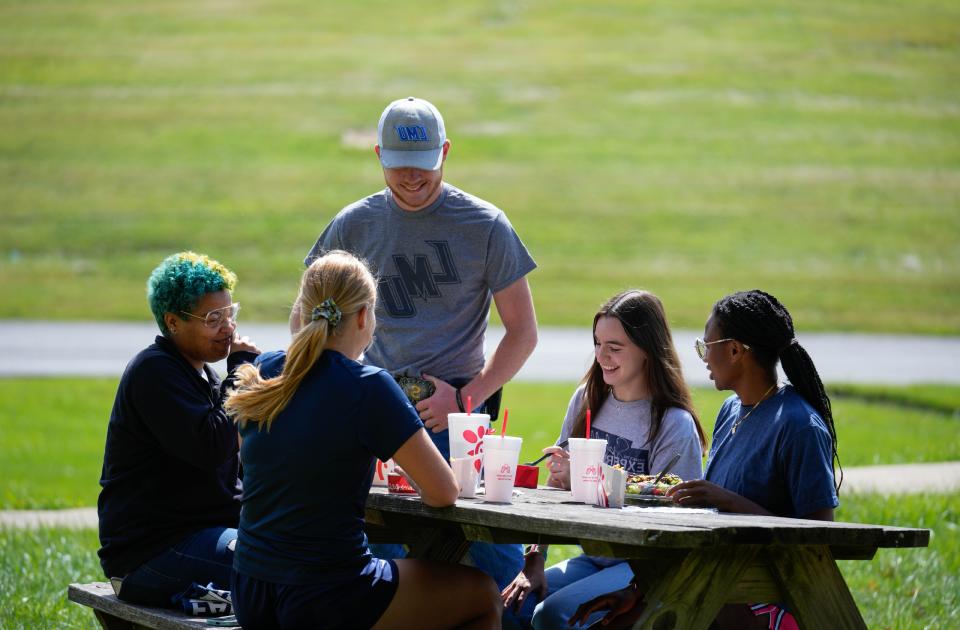 A group of students having lunch at a picnic table. 